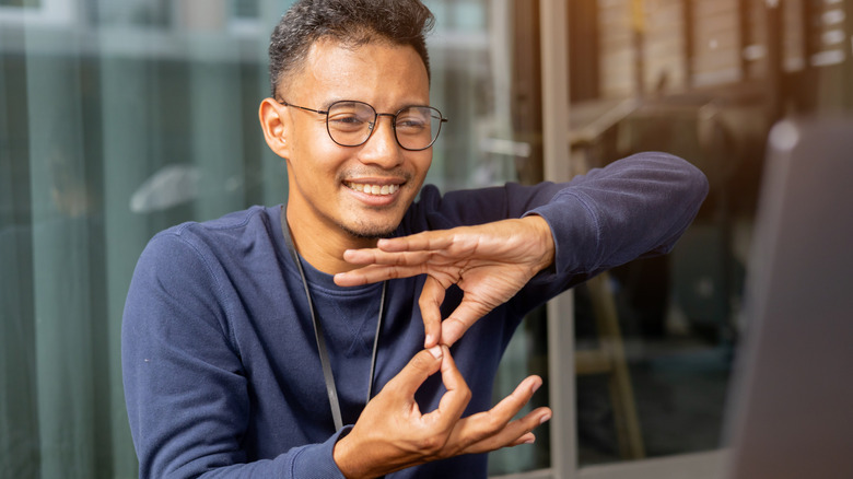 Man practicing sign language in front of his computer