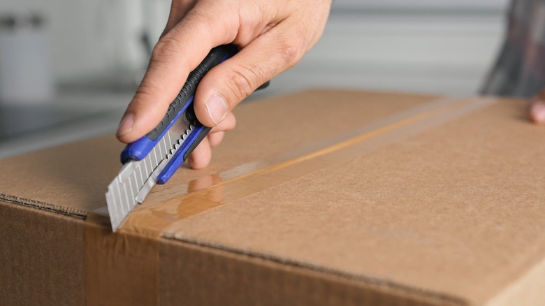 A person using a box cutter to open a package