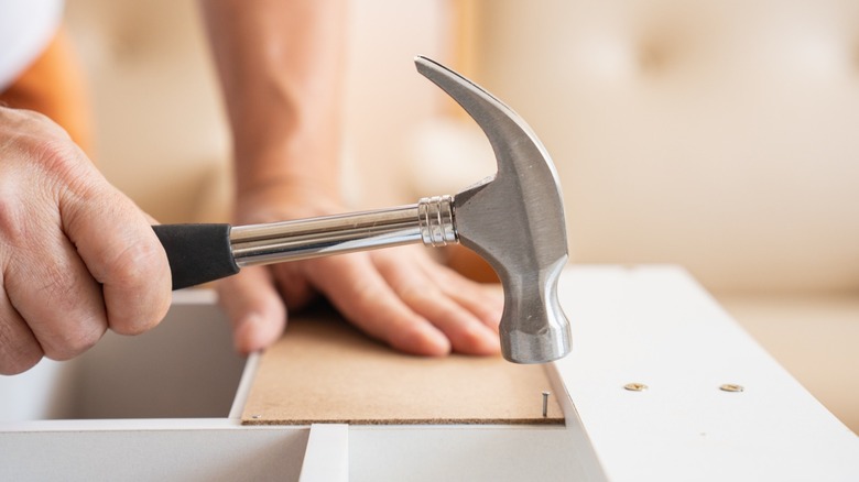 A person hitting a small nail with a hammer