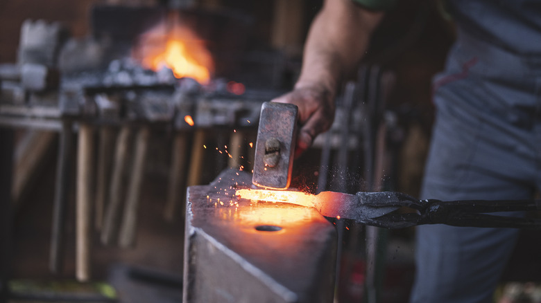 man forging metal knife blade tang