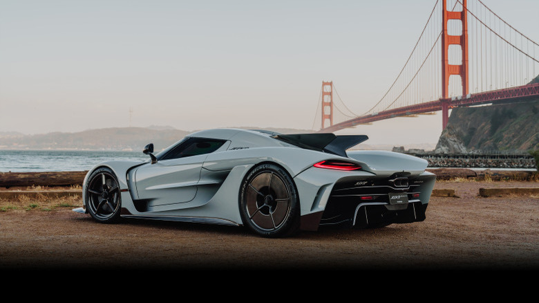 A gray Koenigsegg Jesko Absolut parked in front of a suspension bridge