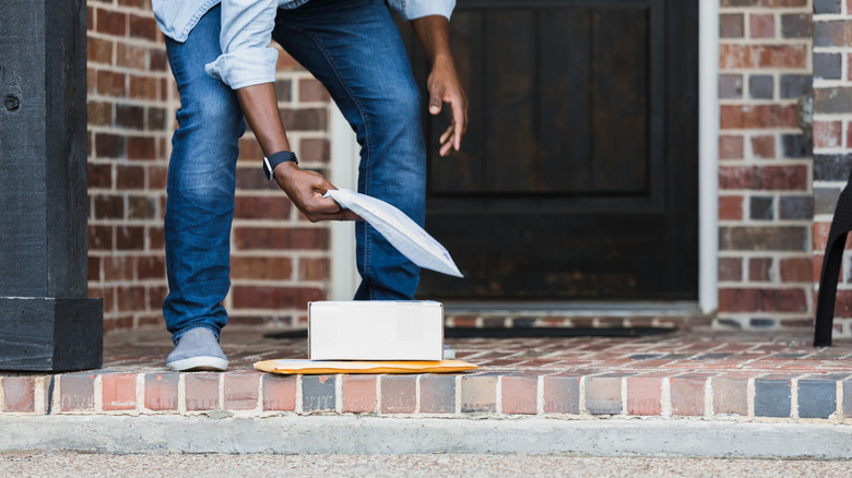 Man picking up small package in front of house