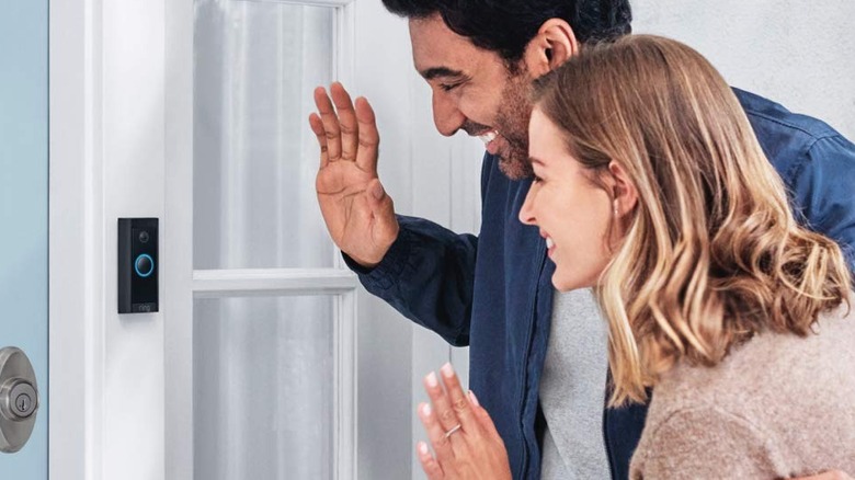 Man and woman waving at Ring doorbell