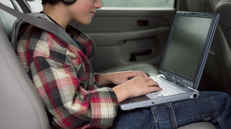 boy using laptop in car