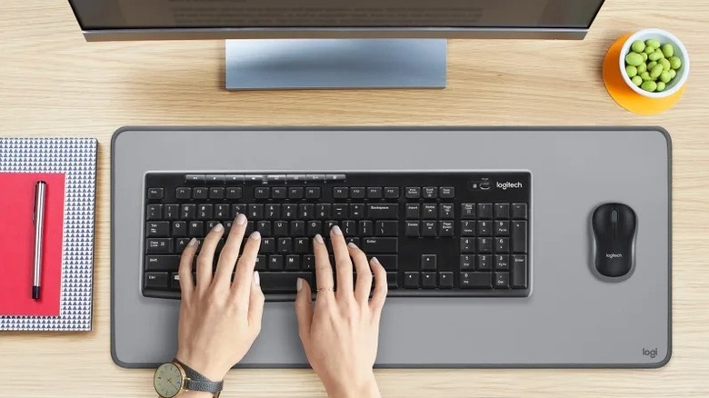 hands on Logitech keyboard next to mouse