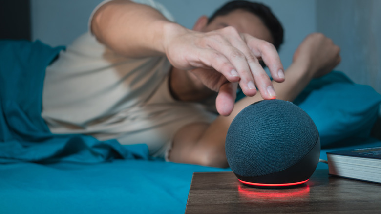 Man in bed tapping on Echo Dot