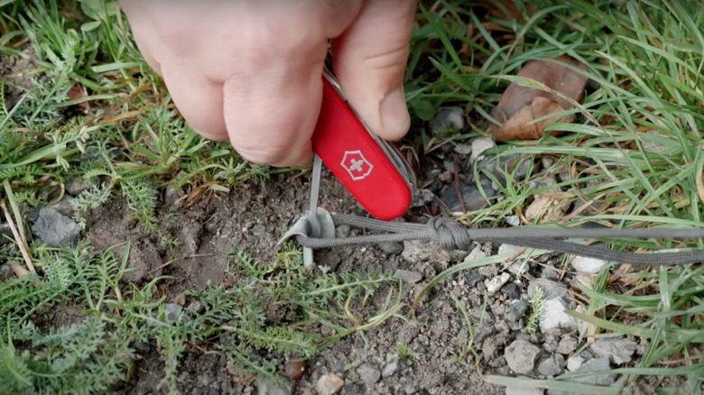 Tent hooks being pulled out by a Swiss Army knife