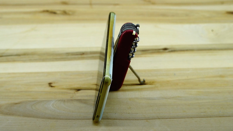 Swiss Army knife holding up a phone on a wood tabletop