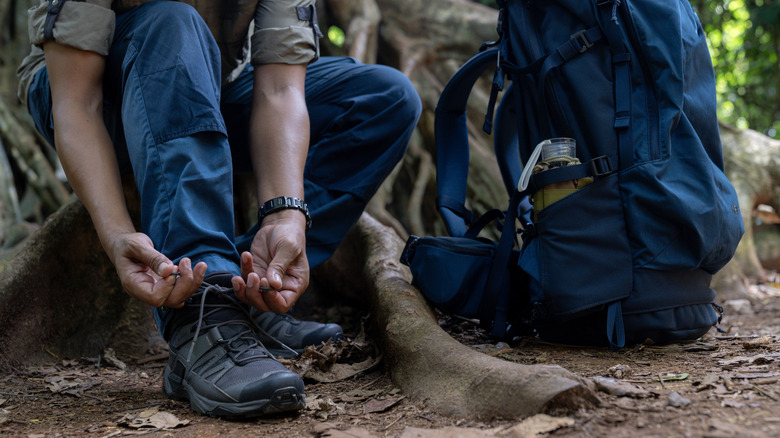 Man tying his hiking boots in the woods