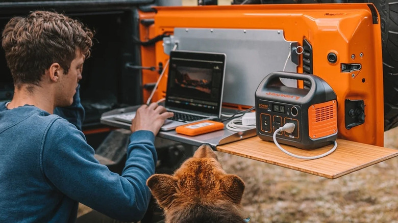 person with dog using Jackery Explorer 290 to power laptop 