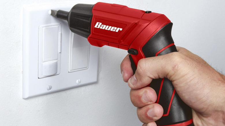 Electric screwdriver being used on a light switch cover