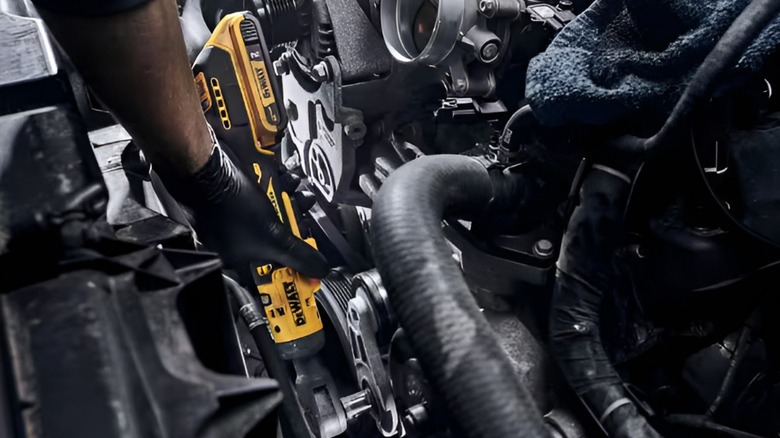 A person using a DeWalt cordless ratchet on what appears to be their serpentine belt tensioner