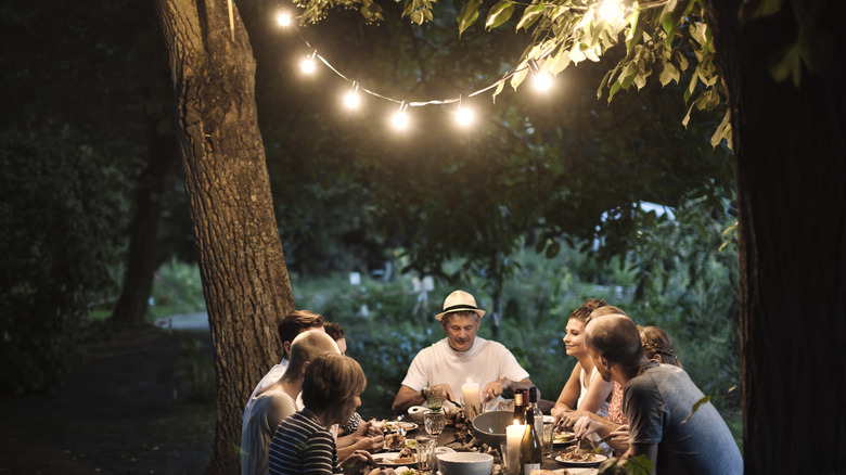 A family having dinner with a set of outdoor lights