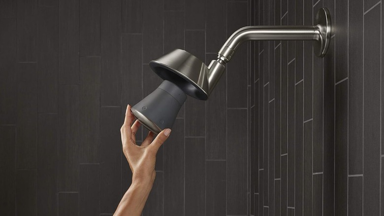 A person installing the wireless speaker in their Kohler Moxie showerhead