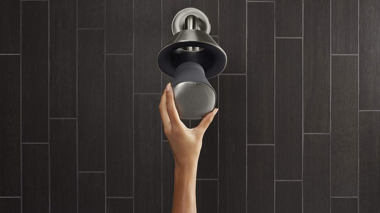 a person installing the wireless speaker into their kohler moxie showerhead