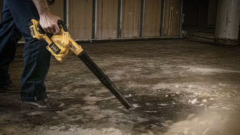 Person using compact blower on debris