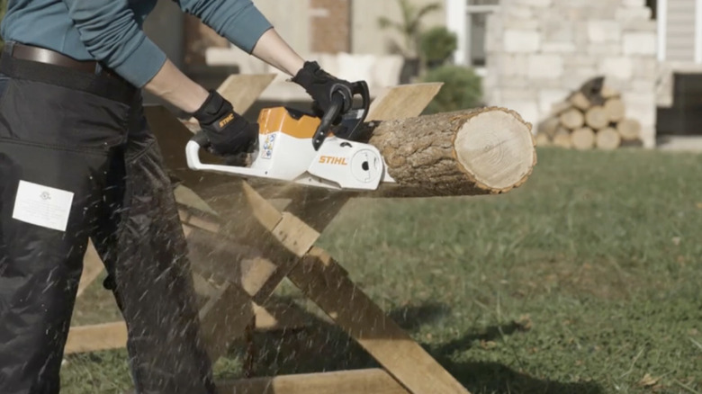 Person using chainsaw on log