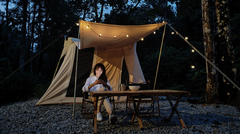 woman using phone near tent