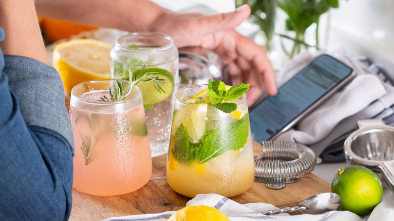 Person using phone next to cocktails