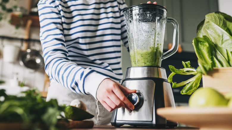 woman blending greens in blender