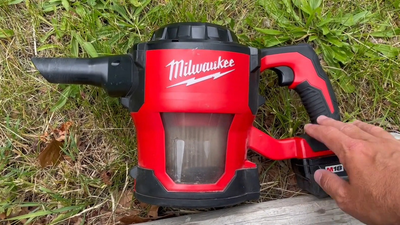 Milwaukee handheld vacuum laying on its side in the grass