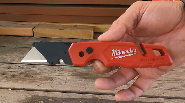 Man holding unsheated Milwaukee utility knife