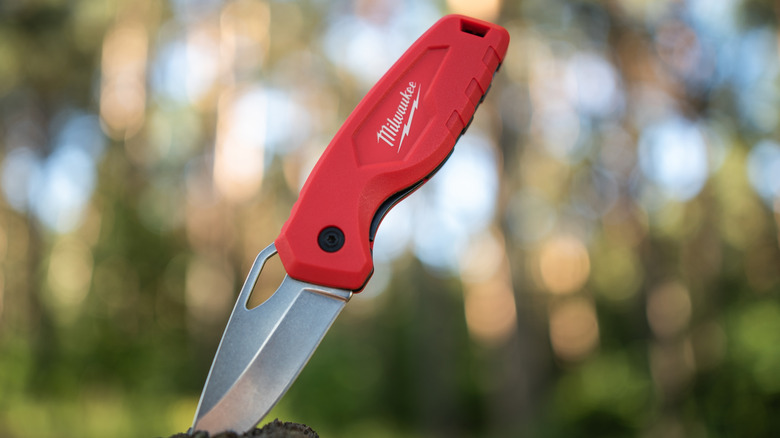 Milwaukee knife sitting upright in wood stump