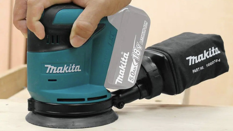 Person using an orbital sander on wood