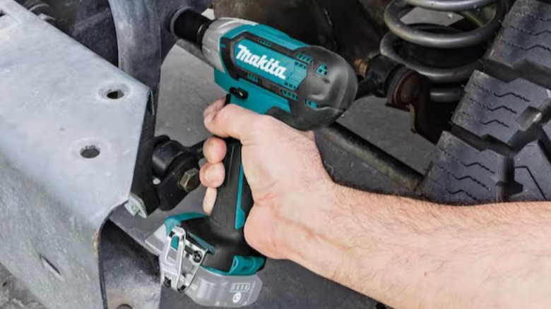 Person using impact wrench on car