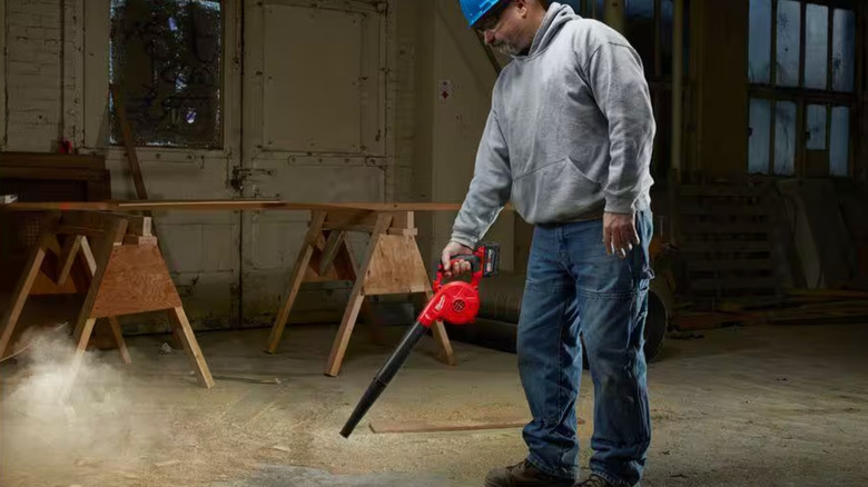 Man blowing debris with power tool