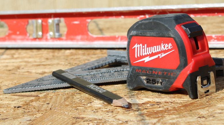 Milwaukee tape measure sitting next to triangle and pencil