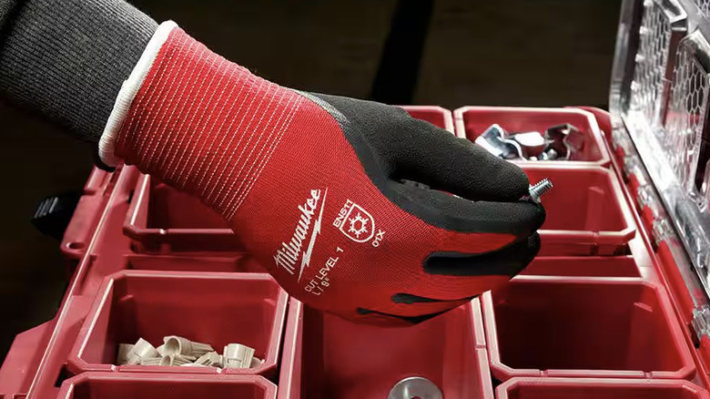 Person wearing Milwaukee gloves while reaching into parts toolbox