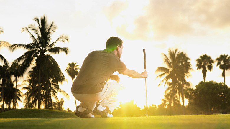 man looking at sunset golf course