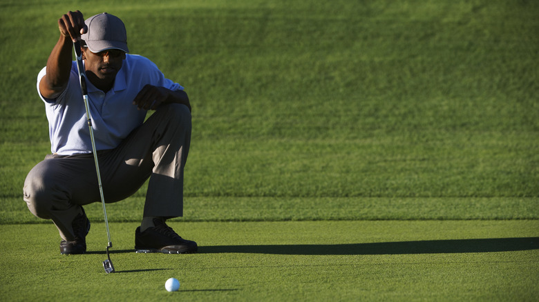 man looking at golf ball