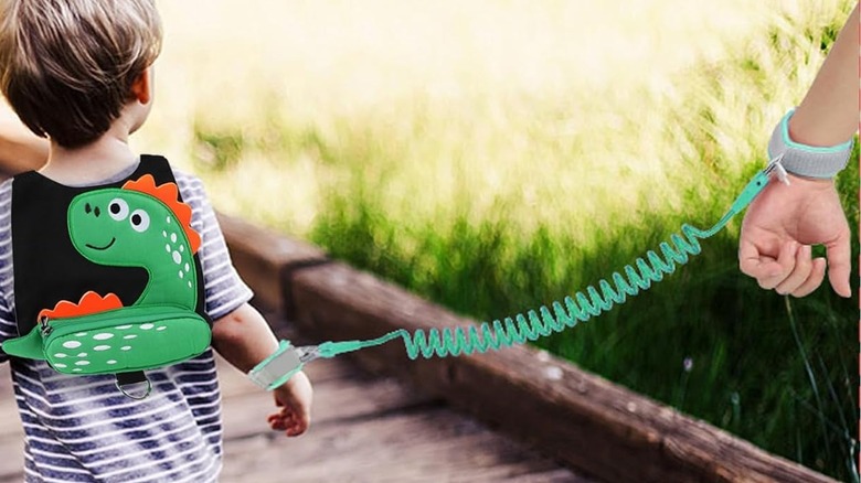 kid wearing a dinosaur baby leash