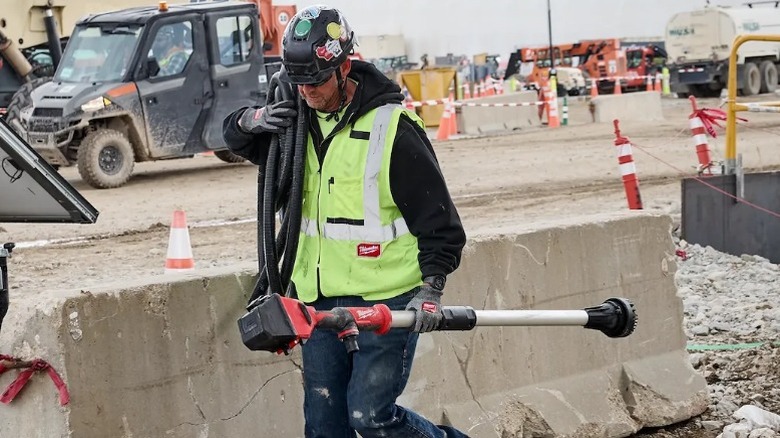 A worker carrying an M18 Brushless Stick Transfer Pump.