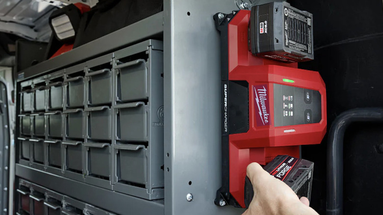 Hand grabbing Milwaukee M18 battery from wall-mounted Dual Bay Simultaneous Super Charger