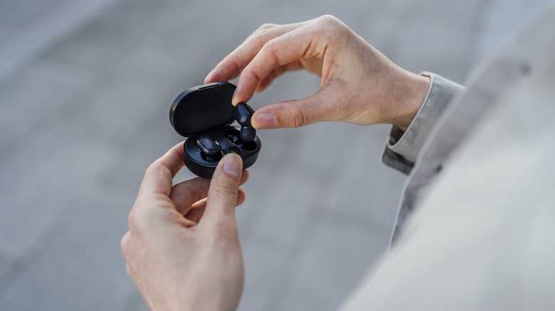 Person placing wireless earbuds in case