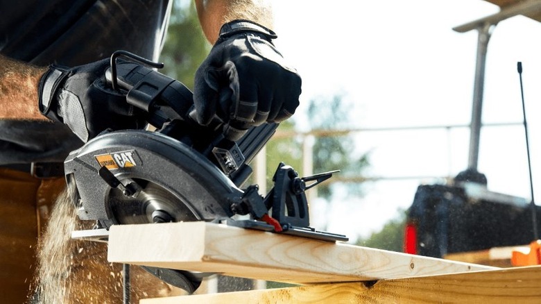 person using Cat 15A 7.25-inch Corded Circular Saw