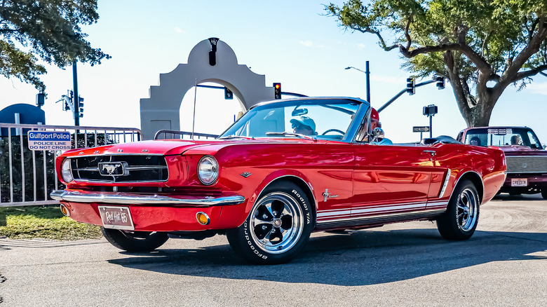 Red Mustang parked next to gate