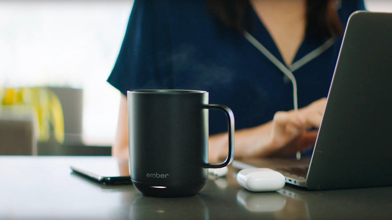 Ember Mug 2 on table next to woman working