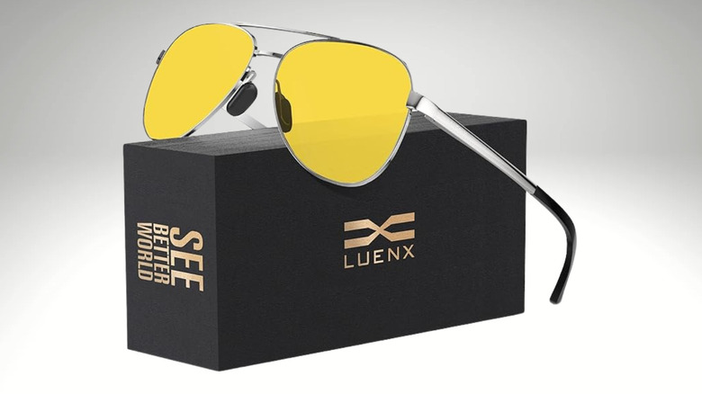 A pair of yellow sunglasses on top of a black box that says "Luenx - See better world"