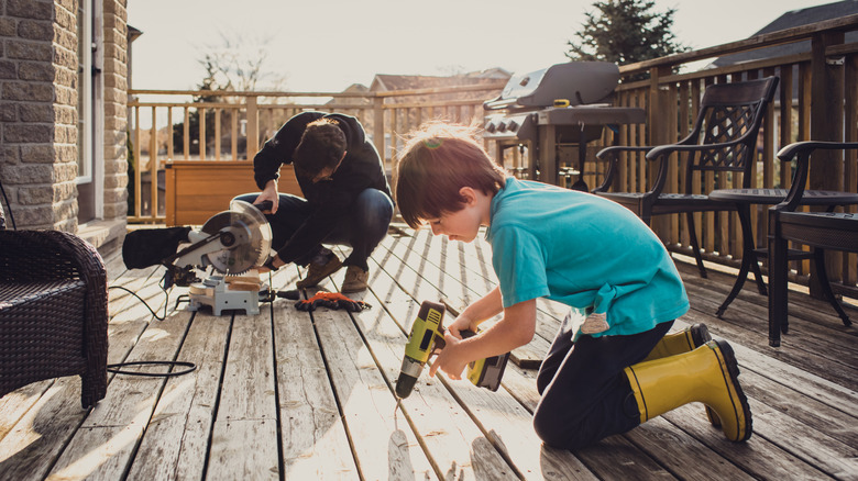 A father and son using power tools to work on a deck