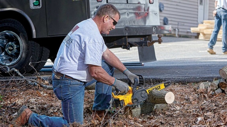 Person using DeWalt 20V Max 12 Brushless Chainsaw on log