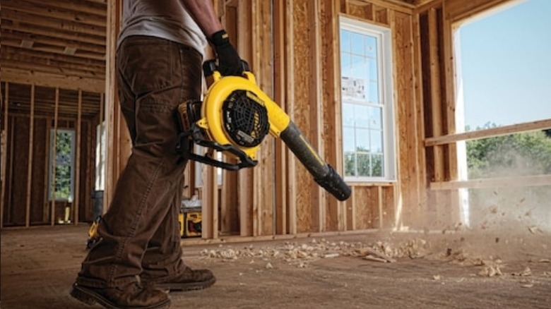 Person using DeWalt 60V Max Handheld Blower to clean house