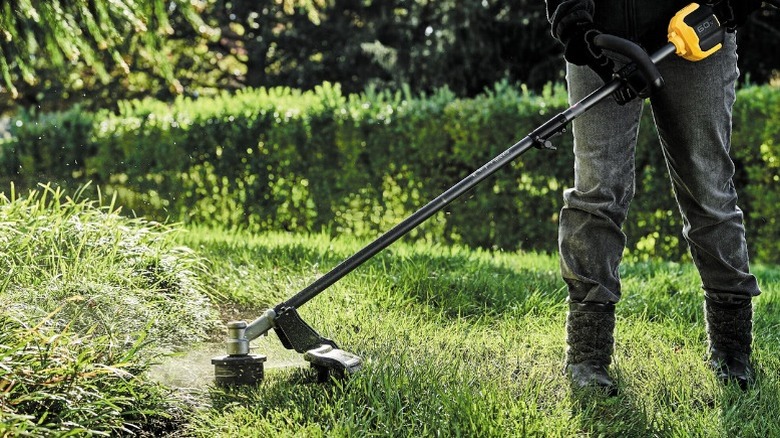 Person using DeWalt Flexvolt 60V Max Attachment Capable Trimmer on grass