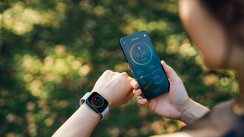 person checking fitness app on phone and smartwatch