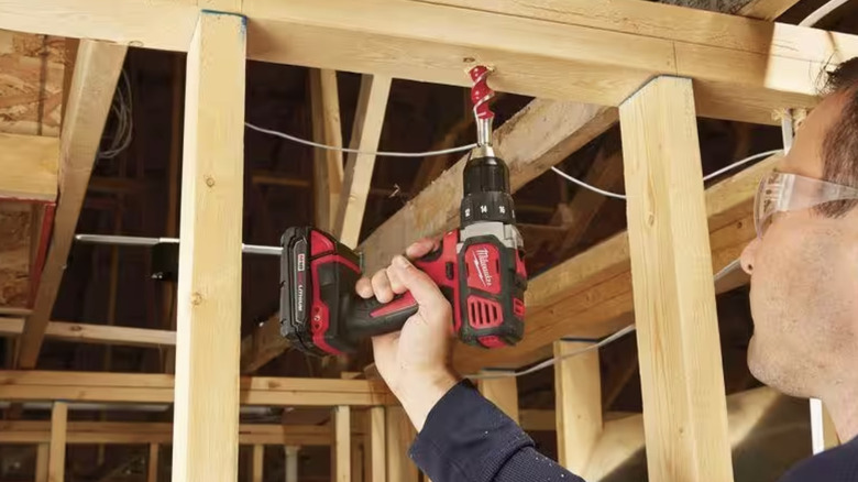 Man using drill to put a hole in wood 