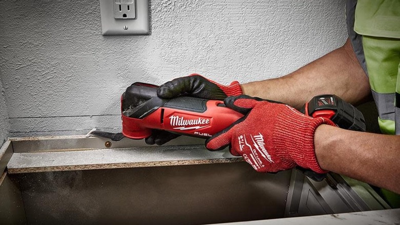 Person cutting into wall with oscillating tool