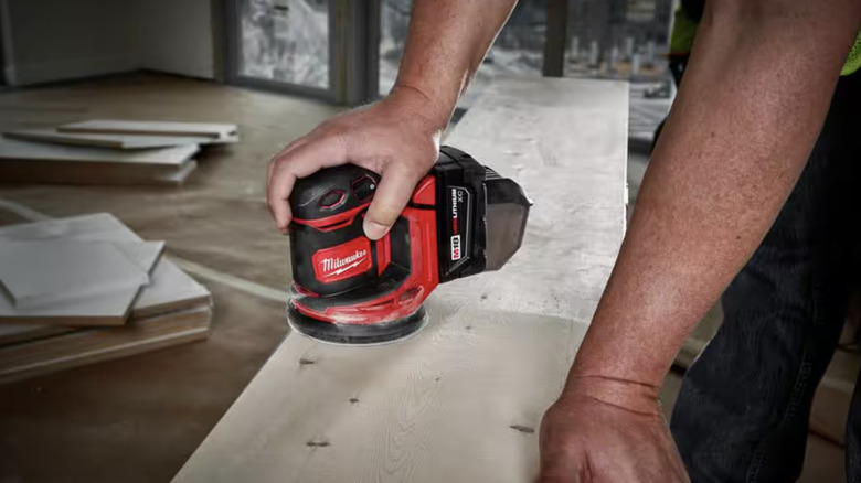 Person using obrital sander to smooth out a piece of wood